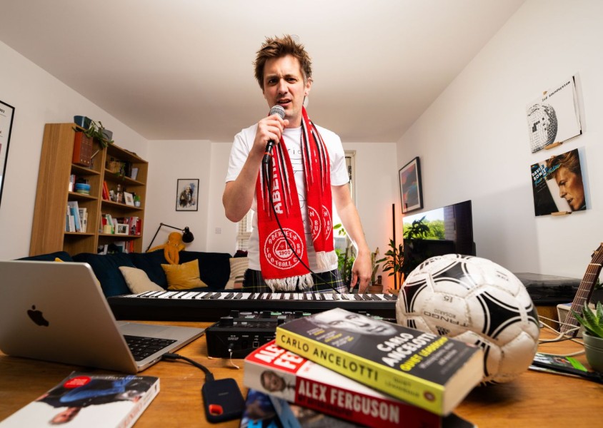 Man wearing an aberdeen FC scarf standing in a living roomx